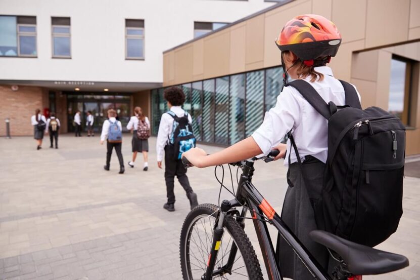 Student arriving at school by bicycle outside a modern educational building