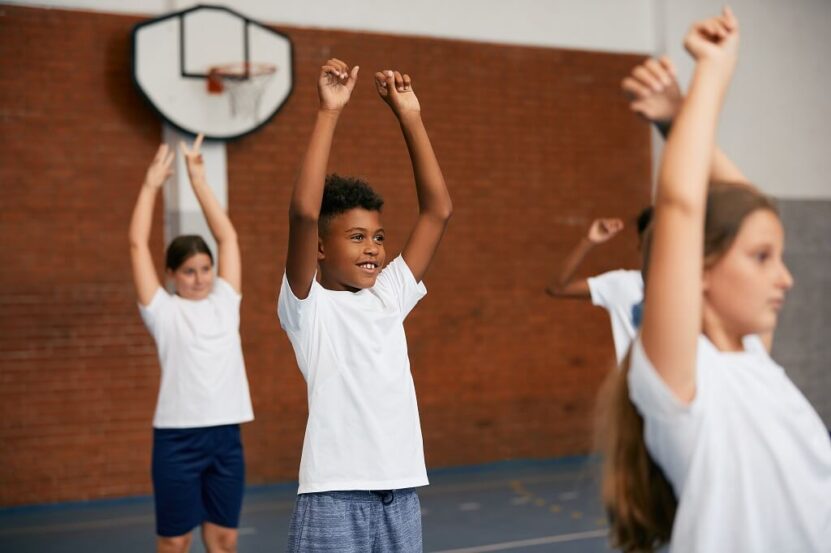 Children participating in physical education activities inside a school sports hall